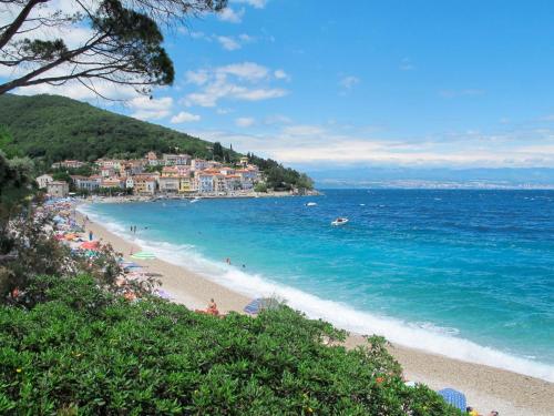 a beach with people in the water and a town at Apartment Branka-1 by Interhome in Mošćenice
