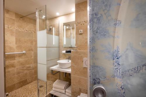 y baño con ducha acristalada y lavamanos. en Relais Hôtel du Vieux Paris en París