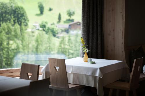 una mesa con un jarrón de flores delante de una ventana en Bühelwirt, en San Giacomo