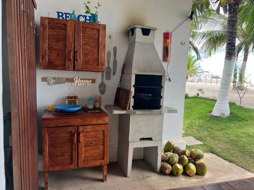 a kitchen with an oven and a table with a pile of fruit at Beira-mar Chácara Curimãs - Barroquinha, Ceará in Barroquinha