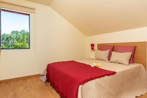 una camera da letto con un letto con una coperta rossa di Comfortable apartment with shared pool in Prazeres, 150 m² a Campanário