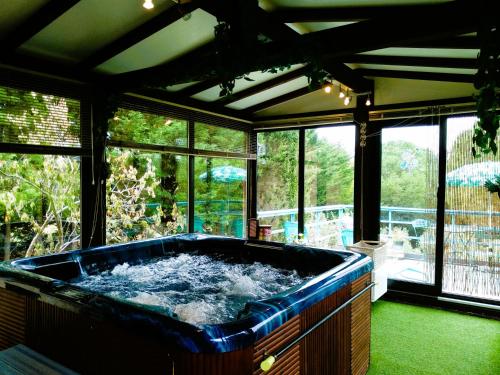 - une grande baignoire bleue dans une chambre avec fenêtres dans l'établissement Gîte en pleine nature - Parc, Piscine, Jacuzzi, à Brézilhac