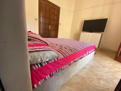 um quarto com uma cama com um cobertor rosa em Comfy private room with big sunny balcony near cairo airport مكان مودرن للاقامة دقائق من مطار القاهرة الدولى no Cairo