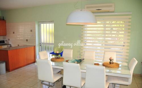 a dining room with a glass table and white chairs at LULA VILLA in Ayia Napa