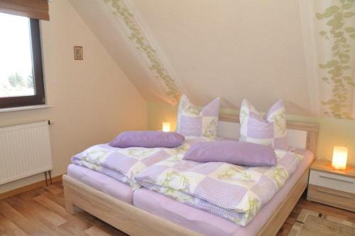 ein Schlafzimmer mit einem Bett mit lila Kissen in der Unterkunft Ferienwohnung "Lindenblick" in Gablenz