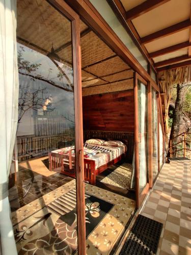 a screened in porch with a bed in it at Sunset Valley Kerala - Where Every Evening Unveils a Perfect Sunset with Private Waterfalls in Pīrmed