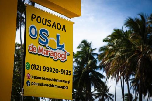a yellow sign on the side of a building with palm trees at Pousada O Sol De Maragogi in Maragogi