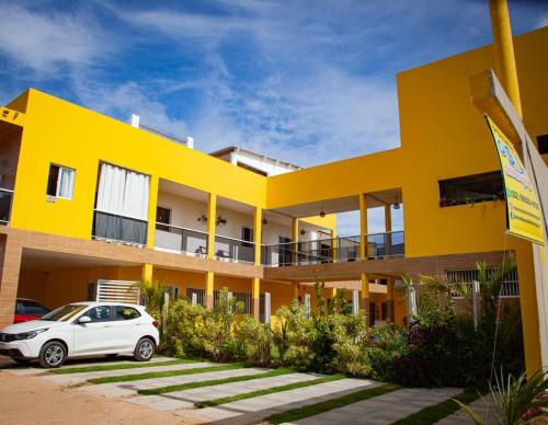 a yellow building with a car parked in front of it at Pousada O Sol De Maragogi in Maragogi