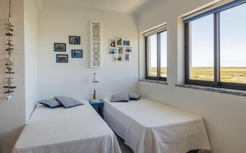 two beds in a room with two windows at Azul in Sagres