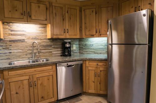 una cocina con nevera de acero inoxidable y armarios de madera en Grand Summit G446, en Park City