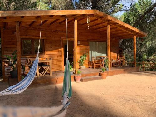 une cabane en rondins avec un hamac en face de celle-ci dans l'établissement CABAÑAS DEL BOSQUE CERCA DE CORDOBA, à Cordoue