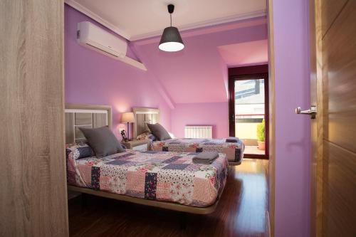 two beds in a room with purple walls at dp Ático Deluxe in Sarria