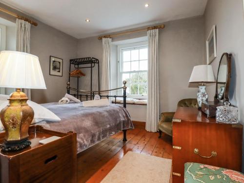 a bedroom with a bed and a desk and a window at Roskorwell Manor in Helston