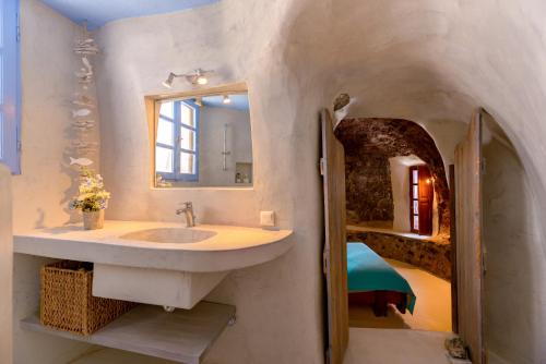 een badkamer met een wastafel, een spiegel en een bed bij Charming Restored 300yr-0ld Guest House in Éxo Goniá