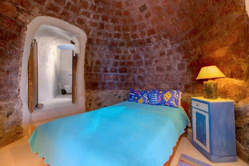 een slaapkamer met een blauw bed in een stenen muur bij Charming Restored 300yr-0ld Guest House in Éxo Goniá