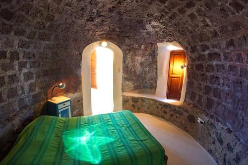 een slaapkamer met een bed in een kamer met een stenen muur bij Charming Restored 300yr-0ld Guest House in Éxo Goniá