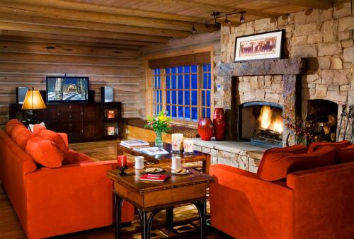 a living room with orange furniture and a stone fireplace at Trappers Cabin in Beaver Creek