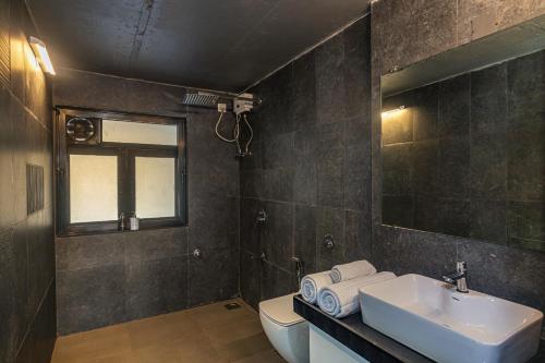 a bathroom with a sink and a toilet and a mirror at SaffronStays Stargazer, Karjat - luxury pool villa with lake view in Karjat