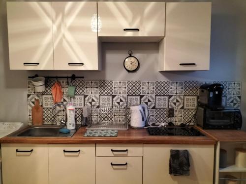 a kitchen with white cabinets and a clock on the wall at Stacja Kocham Morze in Gdańsk