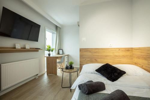 um quarto com uma cama e uma televisão de ecrã plano em WiguryTower Apartaments 70' em Lódź