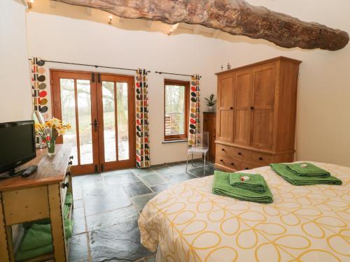 a bedroom with a bed and a desk and a tv at The Threshing Barn in Beaworthy