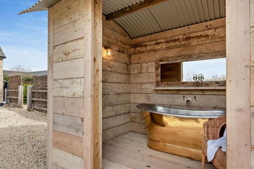 een houten badkamer met een bad en een spiegel bij Owl Barn in Aston