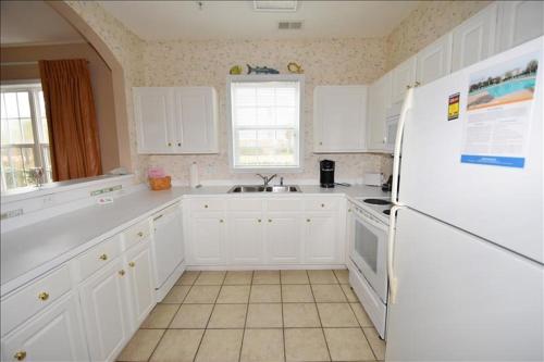 uma cozinha com armários brancos e um frigorífico branco em 1414 Ironwood Condo em Myrtle Beach
