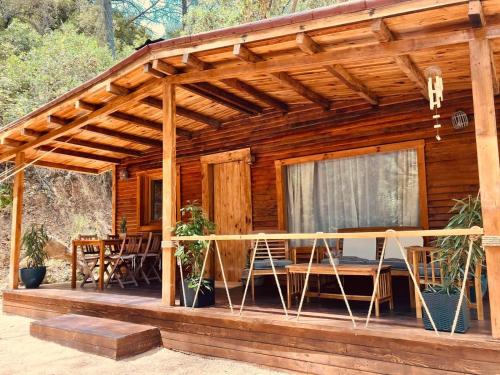 a wooden cabin with chairs and a table on a deck at CABAÑAS DEL BOSQUE CERCA DE CORDOBA in Córdoba