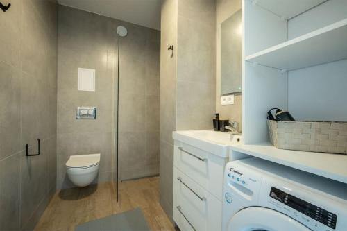 a bathroom with a toilet sink and a washing machine at WiguryTower Apartaments 70' in Łódź