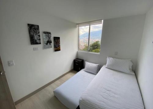 a white room with two beds and a window at Lujoso apartamento en envigado,con hermosa y exclusiva vista in Envigado