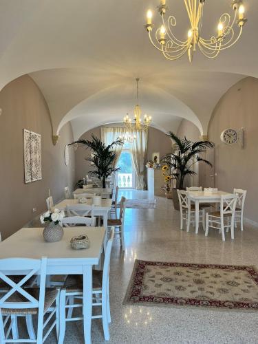 een eetkamer met witte tafels en stoelen en een kroonluchter bij Don Peppe B&B in Monopoli