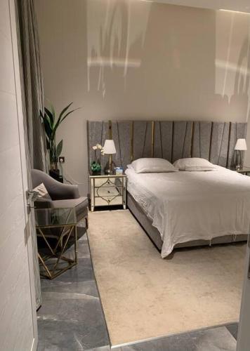 a bedroom with a bed and a chair and lamps at Grey Villa in Buraydah