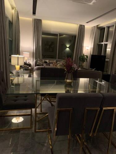 Grey Villa في بريدة: غرفة معيشة مع طاولة وكراسي زجاجية