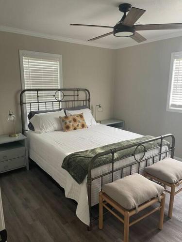 a bedroom with a bed with a fan and two chairs at Piper's Place - 2 Bedroom House in DT Hamilton in Hamilton