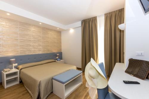 リド・ディ・イエゾロにあるHotel Touringのベッドとデスクが備わるホテルルームです。