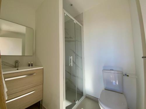a bathroom with a toilet and a glass shower at Les Loges de la Mer - Pérols in Pérols