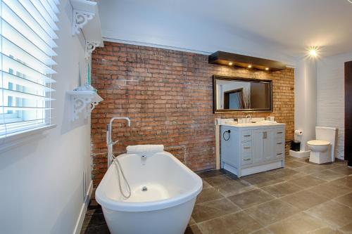 ein Badezimmer mit einer weißen Badewanne und einer Ziegelwand in der Unterkunft Les Lofts St-Jo - Par Les Lofts Vieux-Québec in Québec