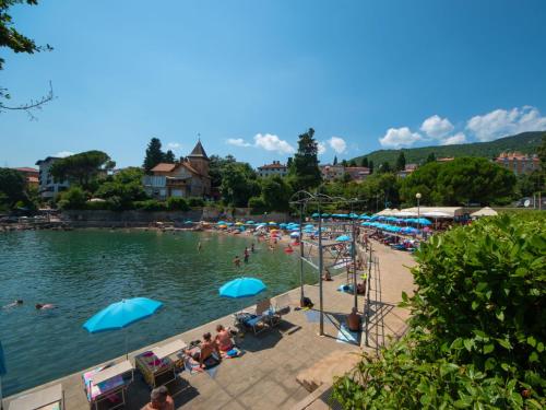 a beach with people and umbrellas in the water at Apartment Deni-1 by Interhome in Volosko