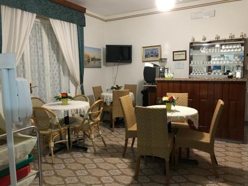 una sala da pranzo con tavoli, sedie e TV di Albergo Europa a Marina di Mancaversa