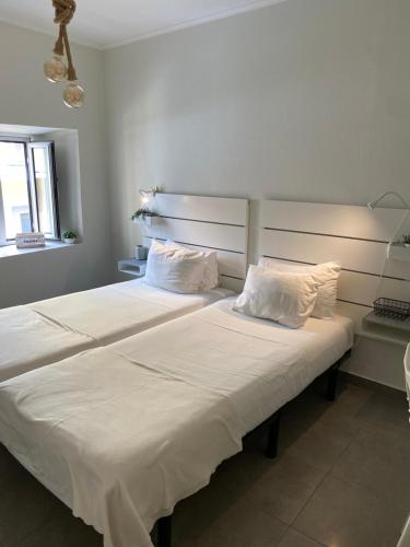 una camera con 2 letti con lenzuola e cuscini bianchi di A Berlenga 2 a Nazaré