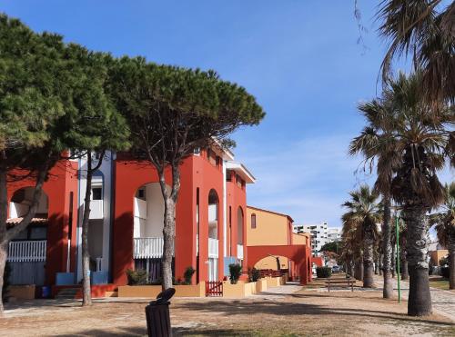 eine Reihe farbenfroher Gebäude mit Palmen in der Unterkunft Appartement en Résidence avec piscine proche mer in Le Barcarès