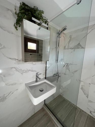 a white bathroom with a sink and a shower at Lucid Dream Apt. Bozinis 2 in Psakoudia