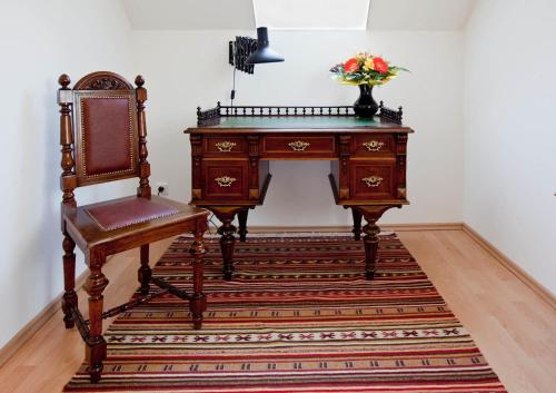 un escritorio de madera con una silla y un jarrón de flores en Ferienhaus Burgenland, en Mönchhof