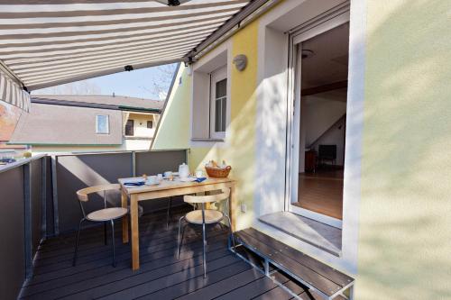 uma pequena varanda com uma mesa de madeira e cadeiras em Ferienhaus Burgenland em Mönchhof