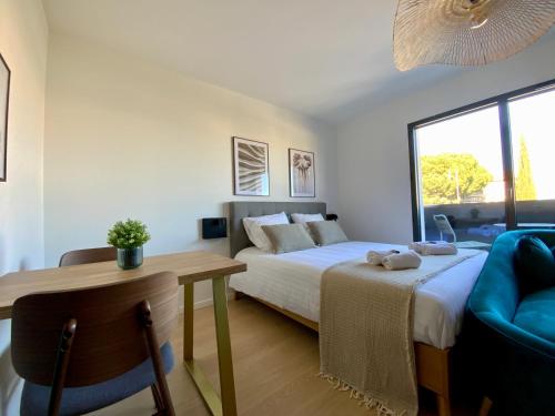 a bedroom with a bed and a table and a couch at Les Loges de la Mer - Pérols in Pérols