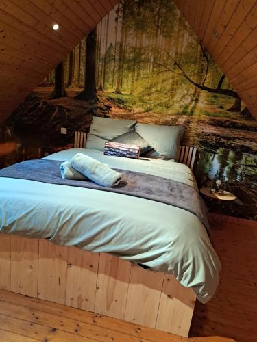 uma cama num chalé de madeira com um mural de árvore em Cottage Le Cabanon em Huisnes-sur-Mer