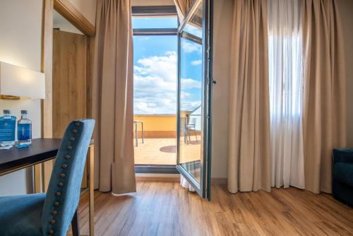 a room with a desk and a view of a balcony at Hotel Zentral Mayoral in Toledo