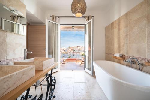 a bathroom with a tub and a large window at La Fabrique à Poupées - Chambres de charme au coeur de Menton in Menton