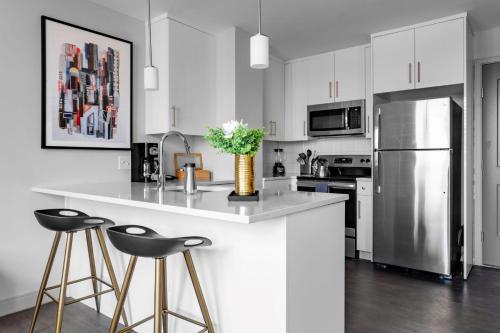 a kitchen with white cabinets and a counter with stools at Downtown Vine St Studio at The Guild in Cincinnati