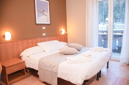 a bedroom with two beds and a window at Hotel La Betulla in Bardonecchia